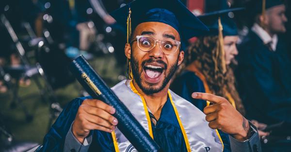 ETSU recent graduate Jahlil White at his commencement ceremony holding his ETSU diploma