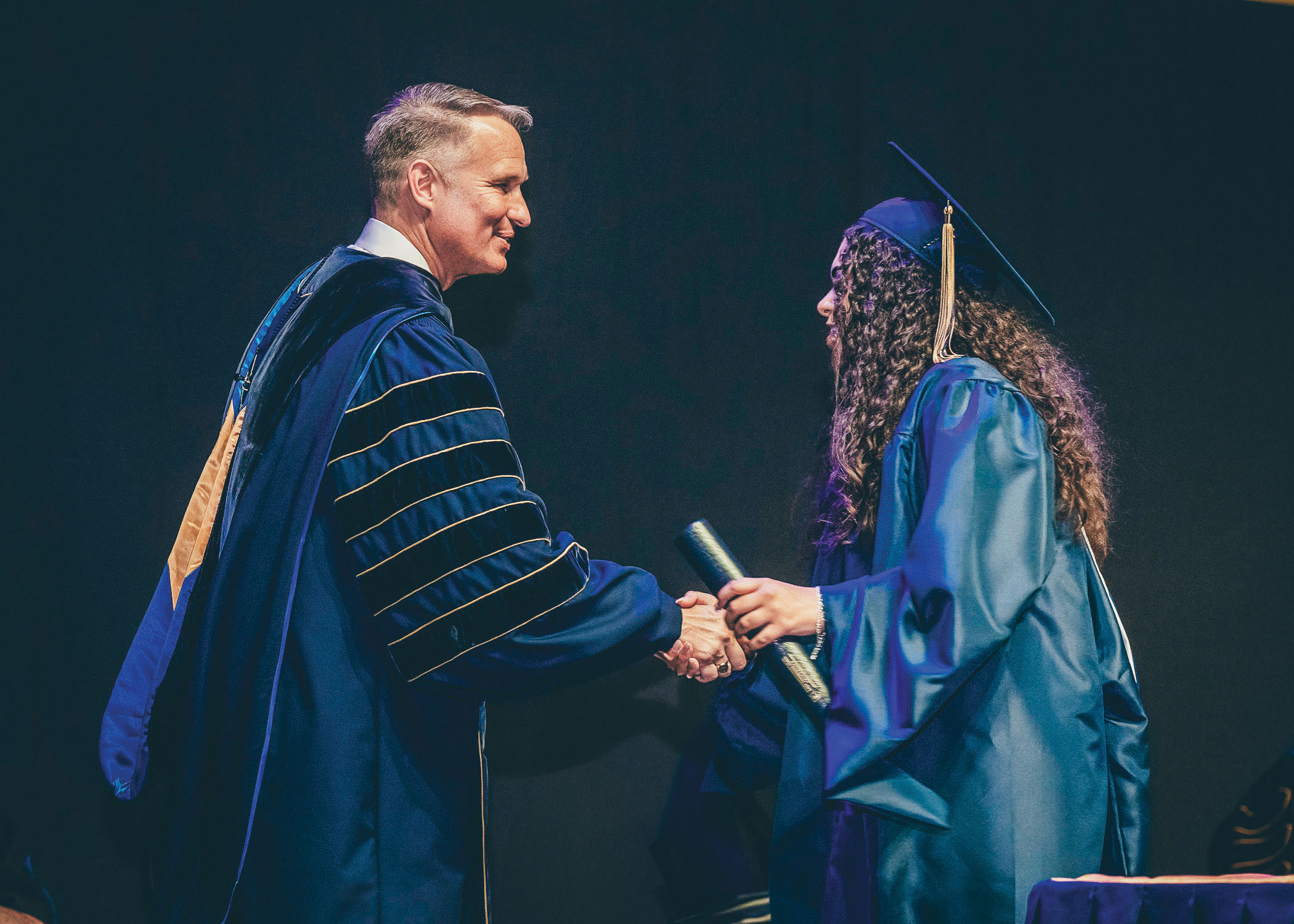 president Brian Noland shakes hands with recent graduate