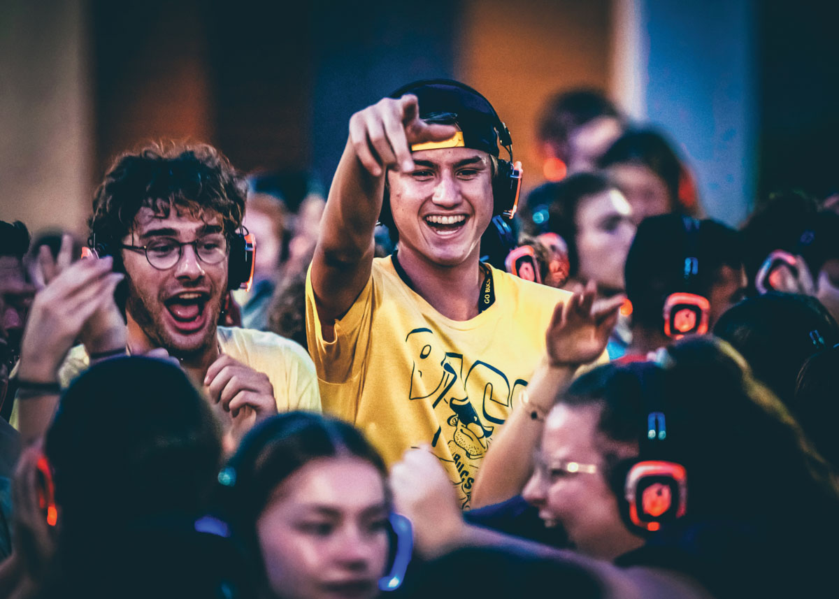 A photo of two students dancing while wearing headphones at a silent disco.