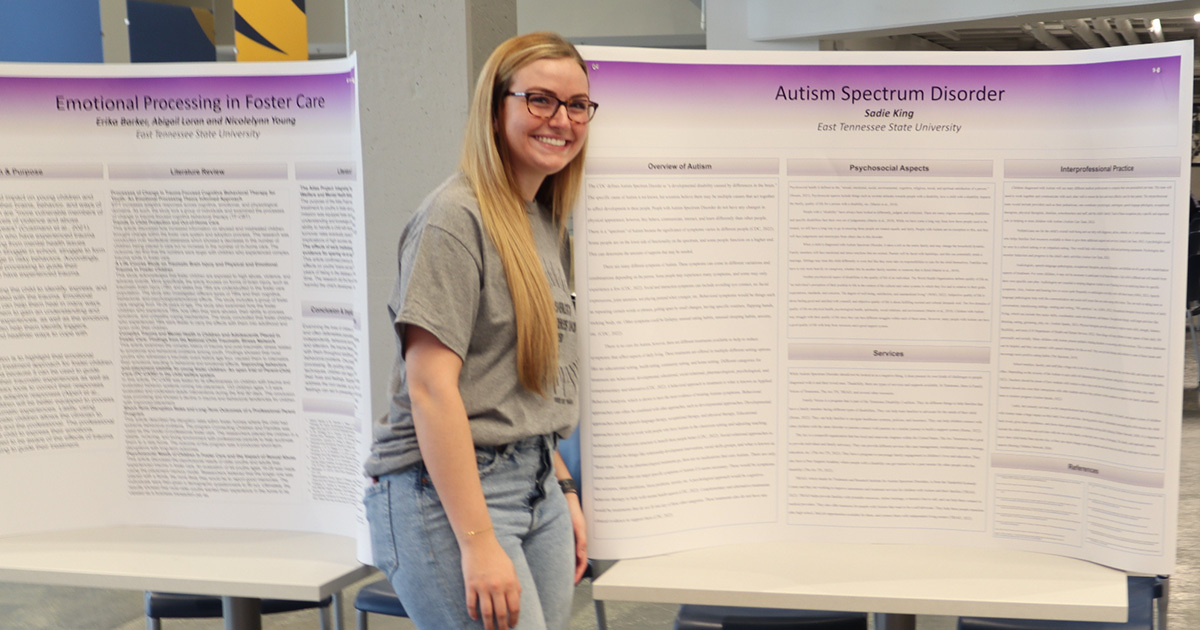 A student stands in front of a poster presentation of Autism Spectrum Disorder. 