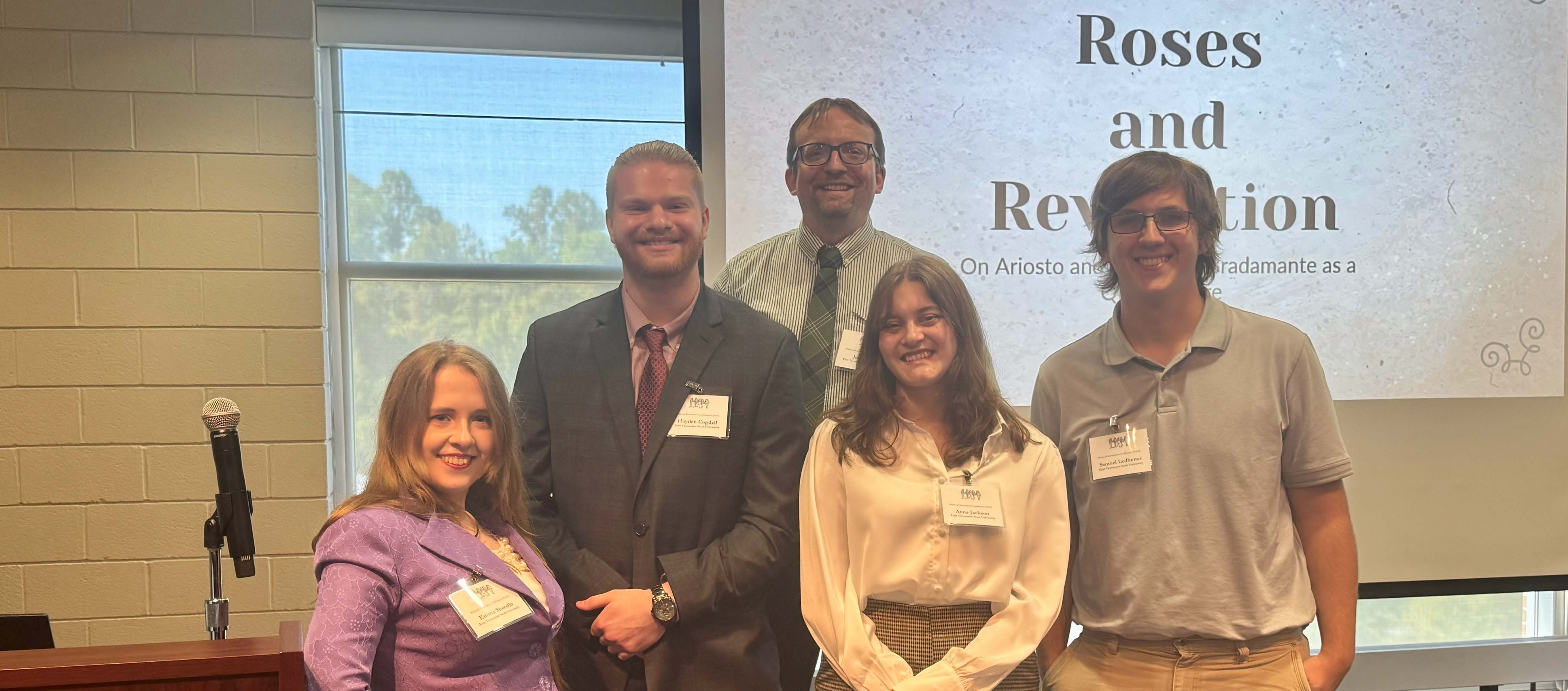 Emma Sheedlo, Hayden Cogdell, Anna Jackson, Samuel Ledbetter, and Dr. Joshua Reid in front of a PowerPoint presentation at the Medieval Renaissance Conference.