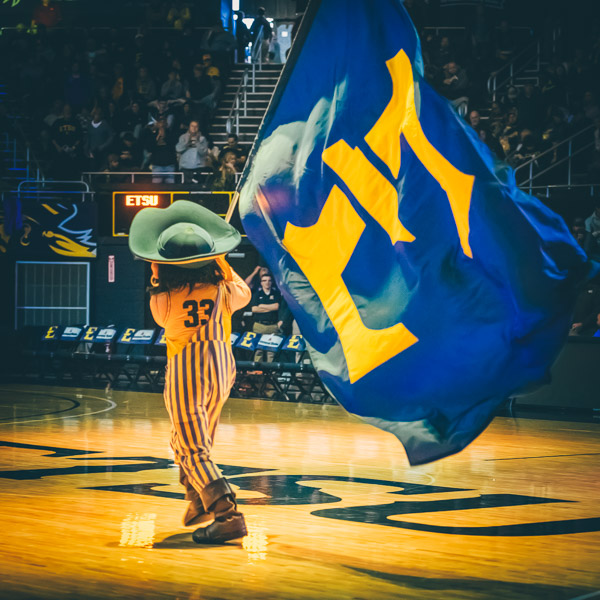 Bucky waving an ETSU flag at a pep rally on campus