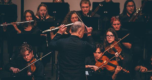 A conductor leading the ETSU orchestra during their concert