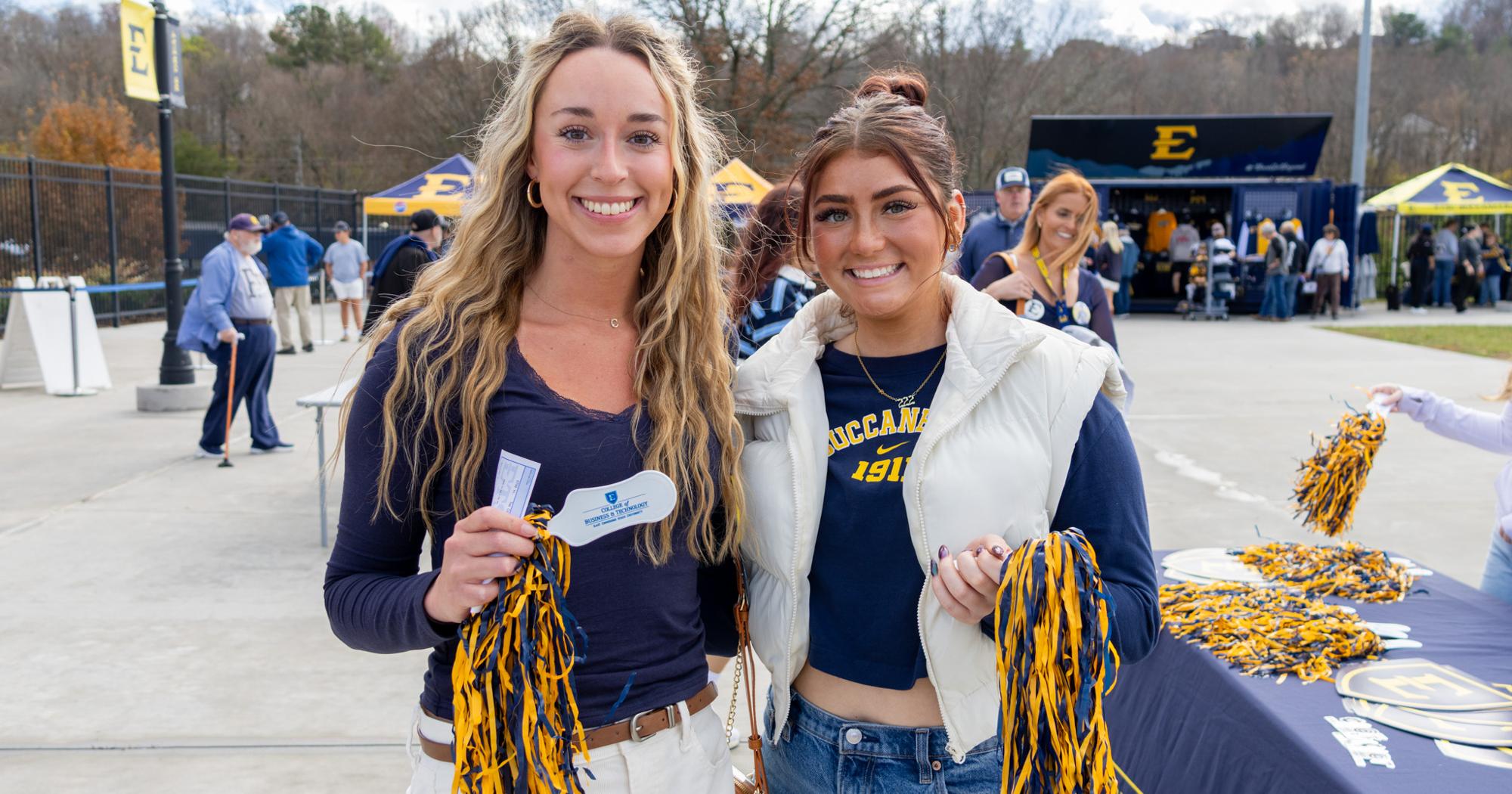Two ETSU CBAT alumni smile at the CBAT Blue Crew football tabling event.