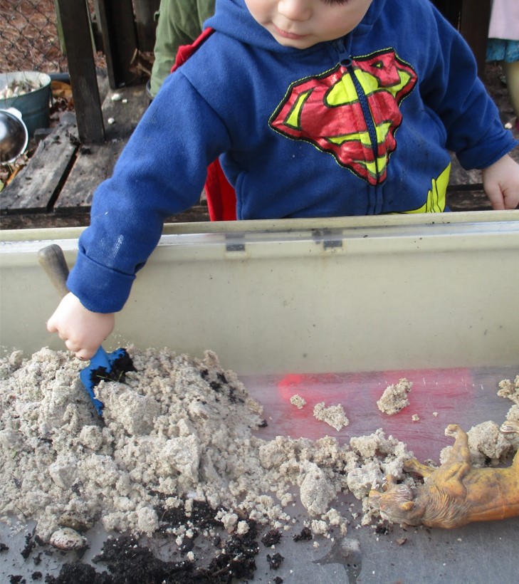 child scooping sand and soil