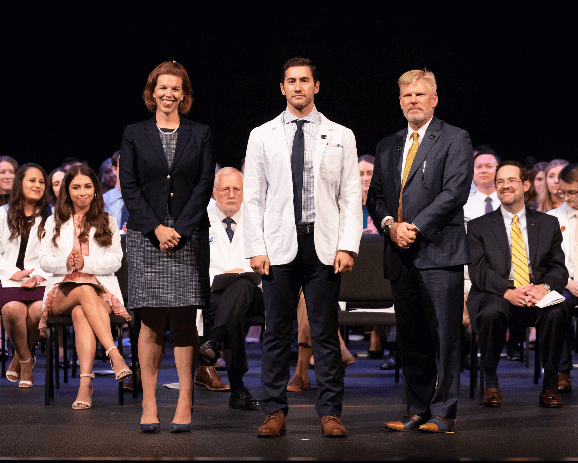 A medical student pictured after receiving his white coat with Dean Block and Dr. Reece.