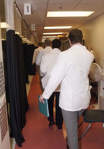 The back of multiple medical students walking with their white coats. 