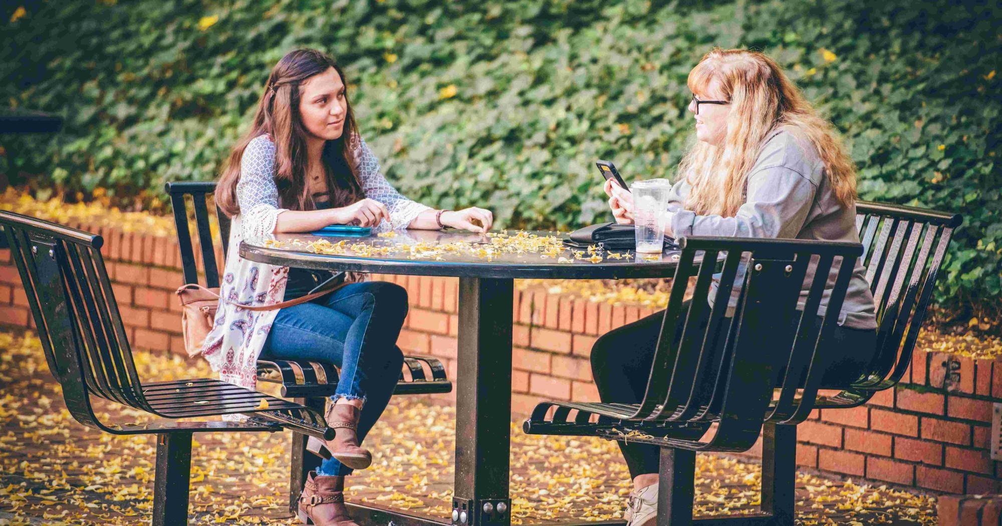 Two ETSU students sit at a table and talk.