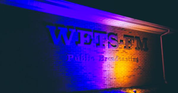 exterior photo of the WETS-FM studio with blue and gold lighting shining on the station's logo