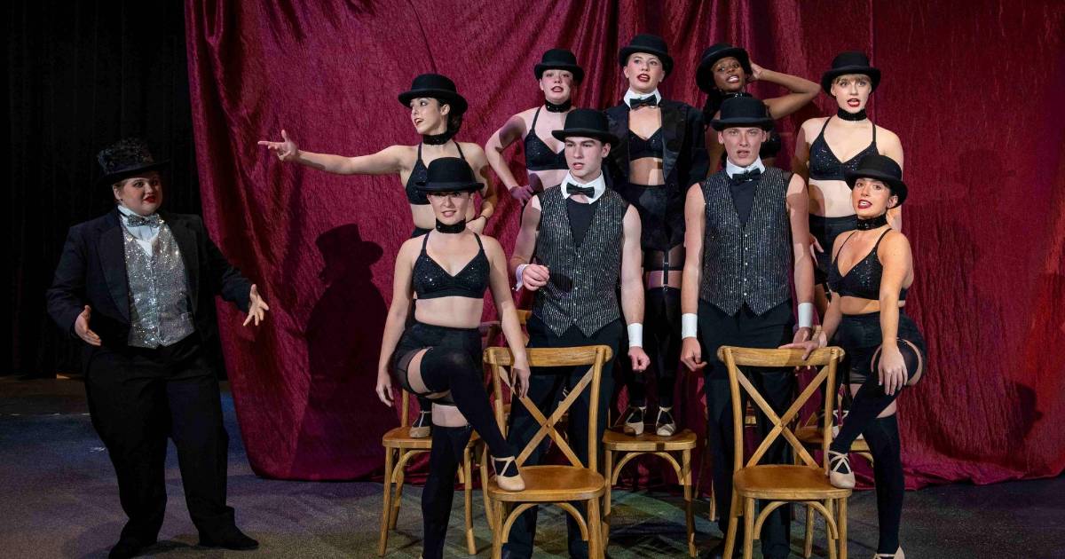  ETSU students performing in 'Cabaret' stand with heads down in chairs while the lead character smiles and looks up. 