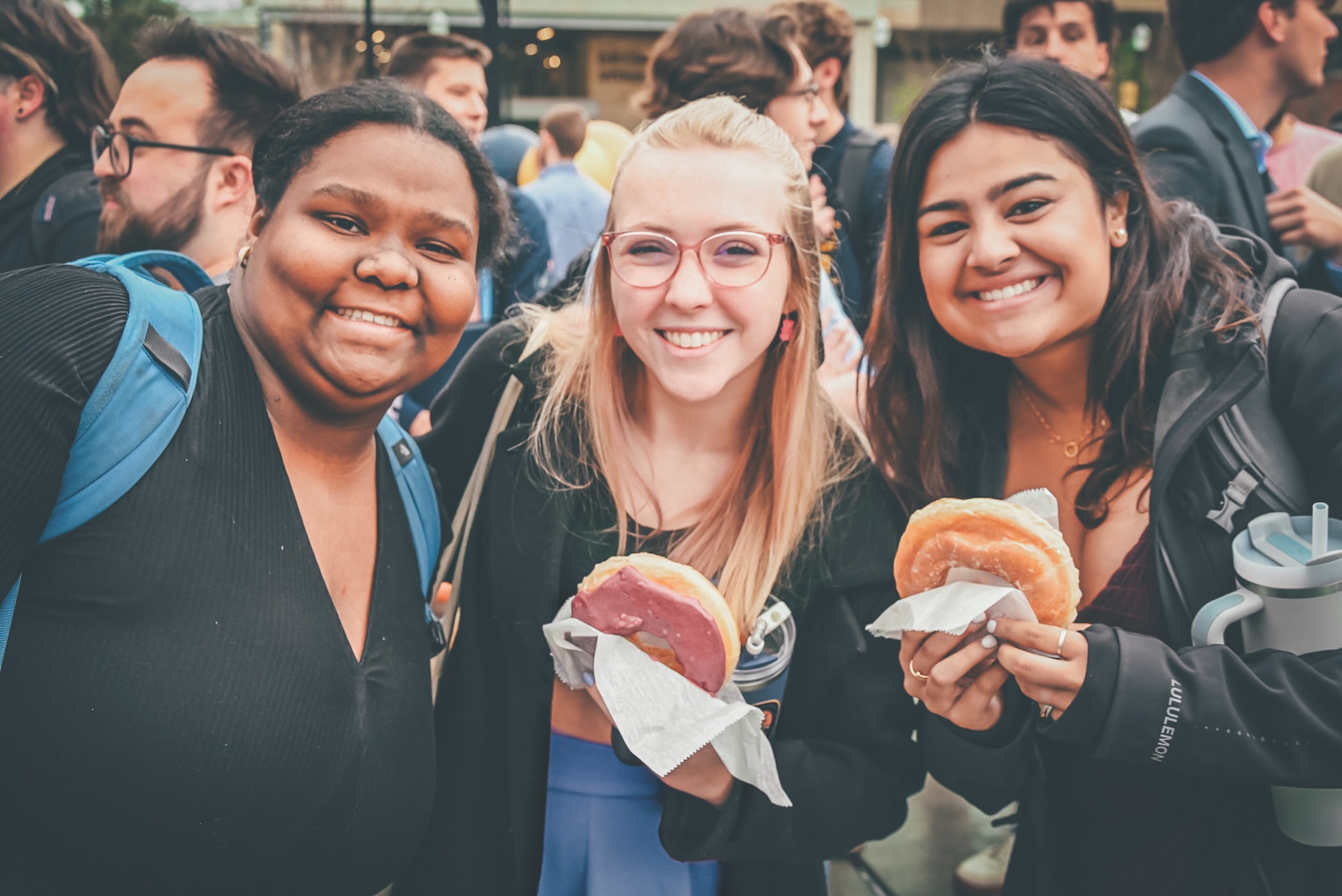 Three students pose with doughnuts at Auntie Ruth’s Doughnuts and Pretzel’s grand opening