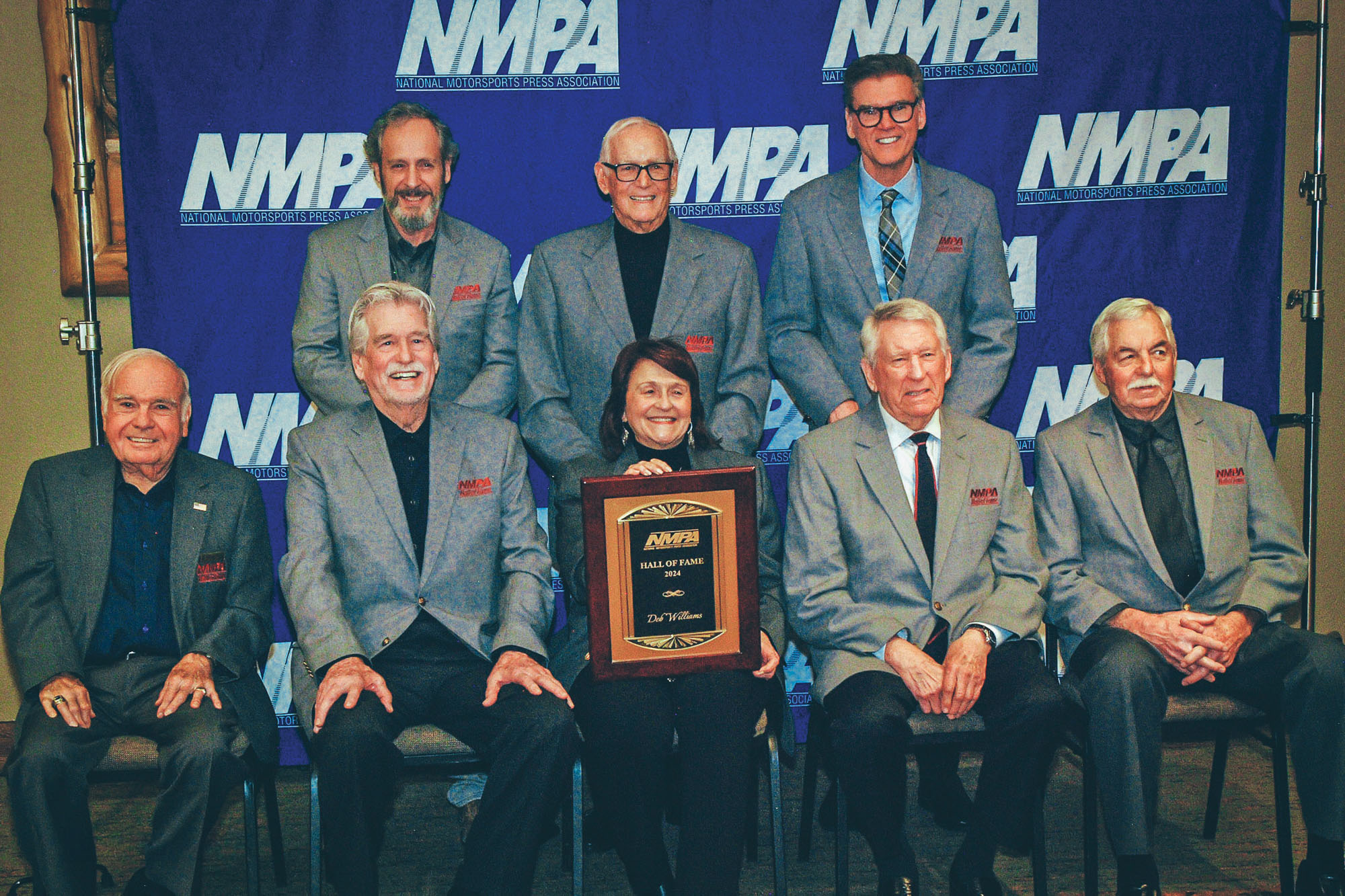 Group photo with Deb Williams in the center holding her award for being inducted into the National Motorsports Press Association Hall of Fame.