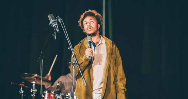 A member of the Gospel Choir holding a microphone and singing. 