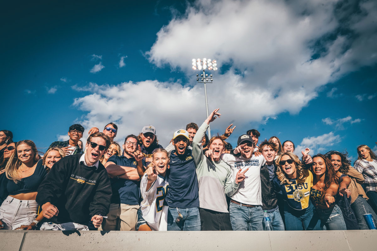 A photo of students cheering at a football game. 