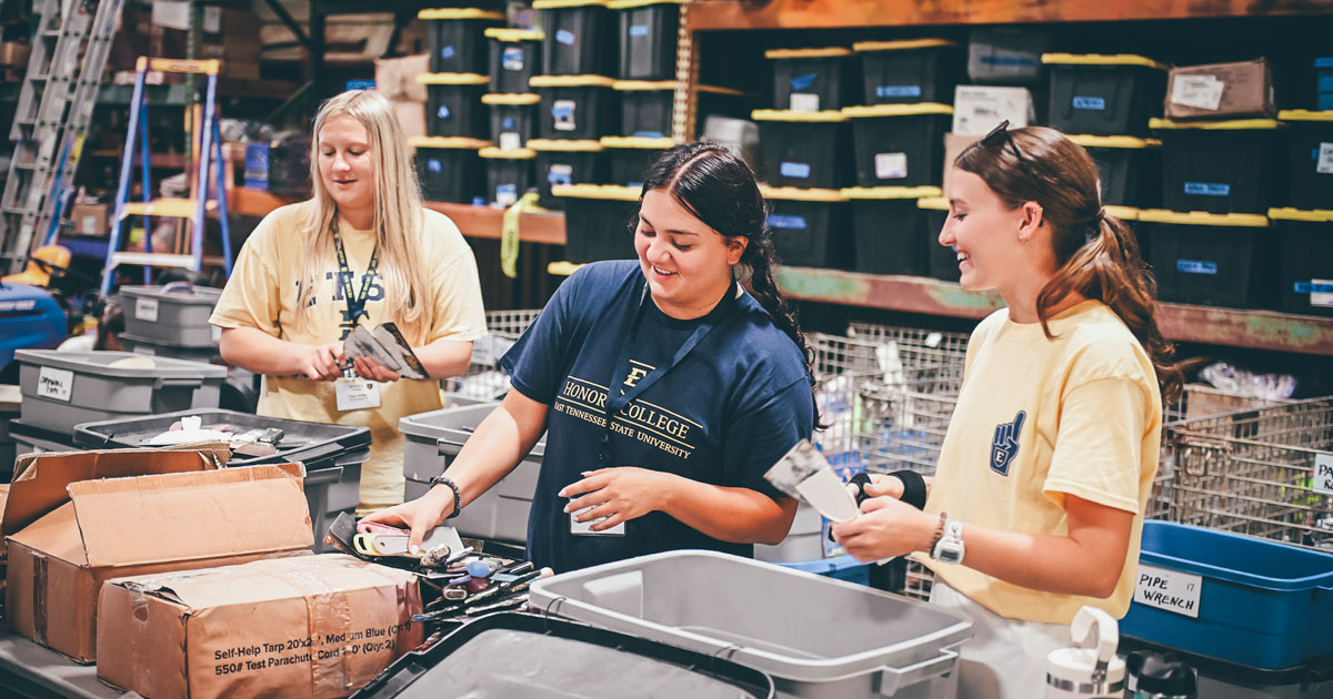 Three students packing boxes of food.